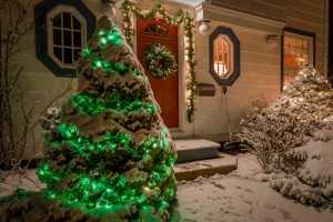 A house decorated with a wreath, garland and Christmas lights an a clear winter night.